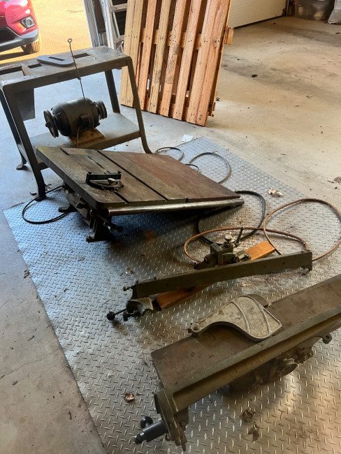 The saw and jointer disassembled on the garage floor